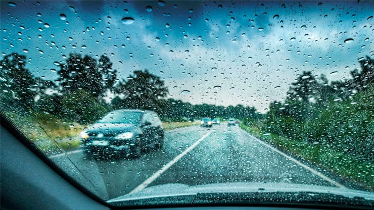 coche circulando con lluvia sobre mojado