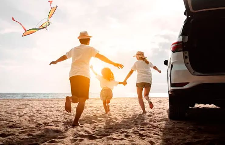 familia en la playa con el coche puesta de sol