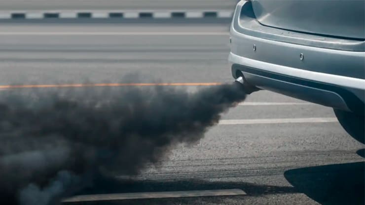 coche expulsando carbonilla en la carretera contaminación